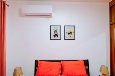 a bedroom with two orange pillows and a white wall at Hermoso apartamento, 3 Habitaciones espaciosas, 2 Aires acondicionados in Santiago de los Caballeros