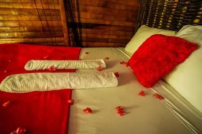 a bed with red and white blankets and leaves on it at Valle Bucana in Santa Bárbara de Samaná