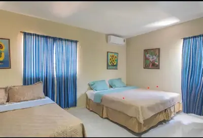 a bedroom with two beds and blue curtains at Villa Luz in Baní