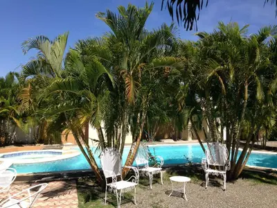 a group of chairs and palm trees next to a pool at Villa Luz in Baní
