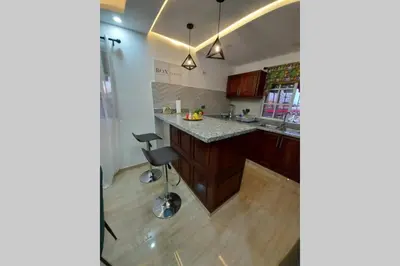 an open kitchen with a counter and a stool at Cómodo Apto de 2hab con Aire 2baños, cerca de todo en Alma Rosa I in El Seis