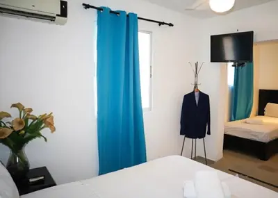 a bedroom with a blue curtain and a suit on a dummy at RIG Casa Conde in Santo Domingo