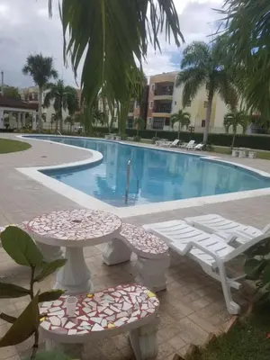 a swimming pool with two tables and chairs in front of it at SANTIAGO PARADISE 111 S 3 in Santiago de los Caballeros