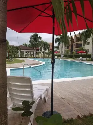 a red umbrella and a white chair next to a pool at SANTIAGO PARADISE 111 S 3 in Santiago de los Caballeros