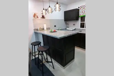 a kitchen with black cabinets and a counter with stools at 4to nivel 2 habitaciones 2 baños Alma Rosa I in El Seis