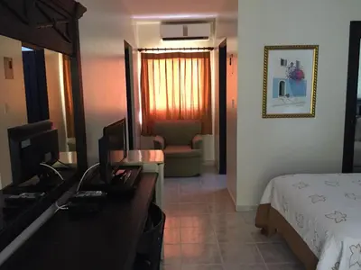 a bedroom with a bed and a desk with a television at Hotel Las Caobas in San Francisco de Macorís