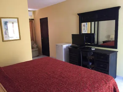 a bedroom with a bed and a desk and a mirror at Hotel Las Caobas in San Francisco de Macorís