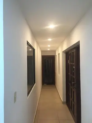 a hallway with white walls and a mirror and a door at Hotel Santander SD in Santo Domingo