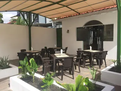 an outdoor patio with tables and chairs and plants at Hotel Santander SD in Santo Domingo