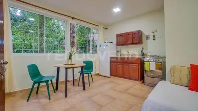 a living room with a table and chairs and a kitchen at El Yaguacil Aparta Hotel in Jarabacoa