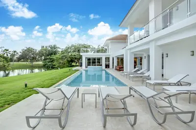 a patio with white chairs and a swimming pool at Best Private Cocotal Villas in Punta Cana in Punta Cana