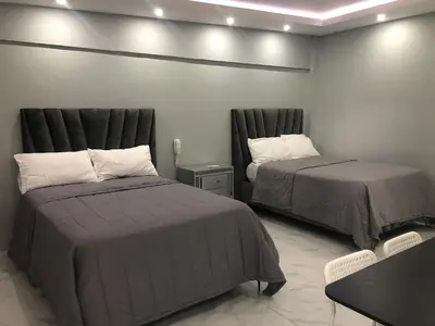 a bedroom with two beds and a table and a table at Hotel Señorial in Santo Domingo