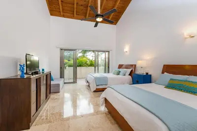 a bedroom with two beds and a flat screen tv at Casa de Campo Luxury Villas - Private Paradise at La Romana in La Romana