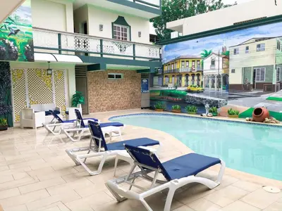 a pool with lounge chairs and a mural of a house at Hotel Sinai in Nagua