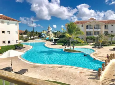 a pool at a resort with palm trees and a building at Paradise Suite Cadaqués in Bayahibe