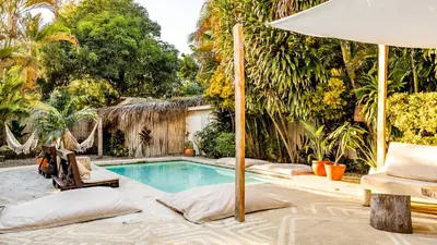 a swimming pool with an umbrella and a chair at Kibayo Lagoon Villa in Cabarete