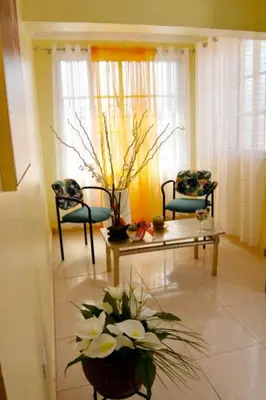 a living room with two chairs and a table and flowers at Acogedor Espacio en Santo Domingo Este. in Mandinga