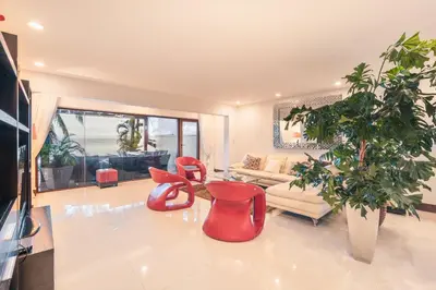 a living room with red chairs and a plant at Townhouse with ocean view Puerto Bahia in Los Grini