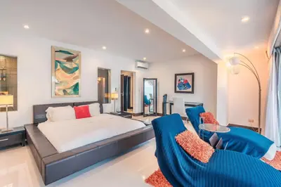 a bedroom with a bed and two blue chairs at Townhouse with ocean view Puerto Bahia in Los Grini
