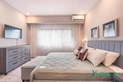 a bedroom with a bed with a dresser and a television at Breakfast Included Fully Serviced Apartment at Regatta Living II - 204 in Santo Domingo