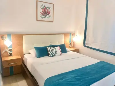 a bedroom with a large white bed with blue pillows at Cana Rock De Lujo 344 Vista Al Campo De Golf in Punta Cana