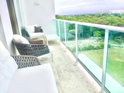 a room with a balcony with a couch and chairs at Cana Rock De Lujo 344 Vista Al Campo De Golf in Punta Cana