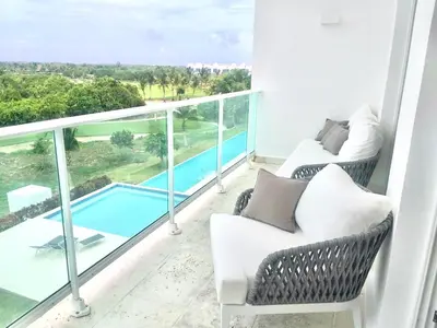 a balcony with two chairs and a swimming pool at Cana Rock De Lujo 344 Vista Al Campo De Golf in Punta Cana
