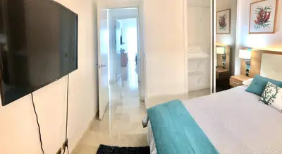 a bedroom with a bed and a flat screen tv at Apartamento 120 Jardin Privado Cana Rock in Punta Cana