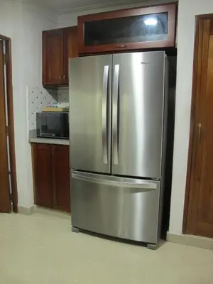a stainless steel refrigerator in a kitchen with wooden cabinets at LEAN LUXURY Santo Domingo in Santo Domingo