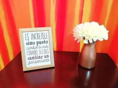 a vase with white flowers on a table next to a sign at Acogedor-Hermoso apart completo equipado de 2 hab. in Santiago de los Caballeros