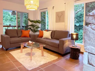 a living room with a couch and a table at Casa del Arroyo 2-Bedroom Cottage Fireplace and BBQ in Jarabacoa