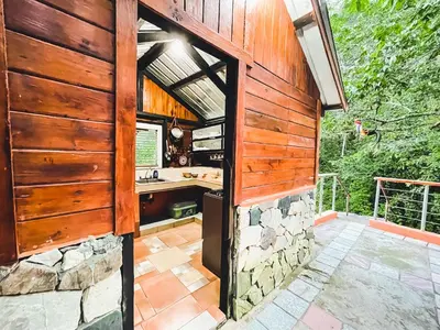 an outdoor kitchen with wooden walls and a stone wall at Casa del Arroyo 2-Bedroom Cottage Fireplace and BBQ in Jarabacoa