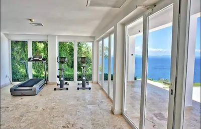 an empty fitness room with a gym with windows at Vista Mare Samana The Best View!! in Santa Bárbara de Samaná
