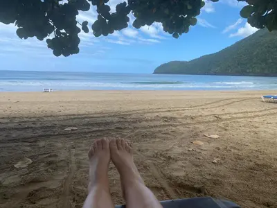 a person sitting on a beach with their feet in the sand at Vista Mare Samana The Best View!! in Santa Bárbara de Samaná