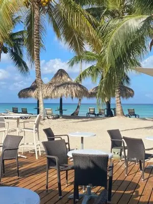 a sandy beach with tables and chairs and palm trees at Cadaques Caribe Bayahibe in Bayahibe
