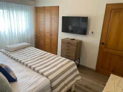 a bedroom with a bed and a dresser and a television at Cadaques Caribe Bayahibe in Bayahibe