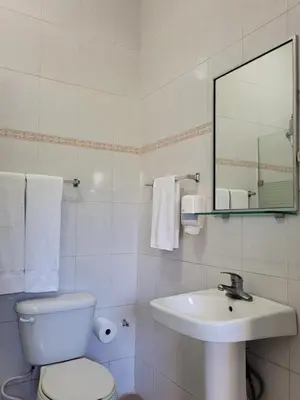 a white bathroom with a toilet and a sink at Drake Bolivar Santo Domingo in Santo Domingo