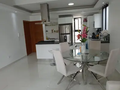 a kitchen with a glass table and white chairs at AMG Suites Apartment in Santo Domingo