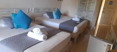 two beds in a hotel room with towels on them at guest house MY WAY in Las Terrenas