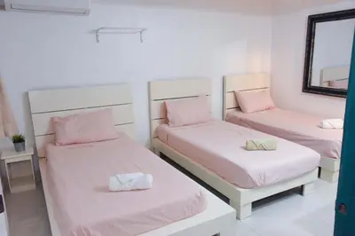 a room with two beds with pink sheets and a mirror at Hostel Gato Colonial in Santo Domingo