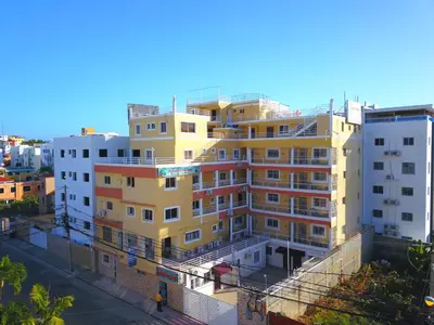 a tall yellow building on the side of a street at Cozy One Bedroom Apartment in Santo Domingo Este in La Viva