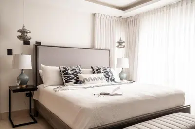 a white bedroom with a large bed with a book on it at Cofresi Hills Residence in Gurapito
