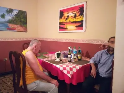 two men sitting at a table with a pink table cloth at La casa de Jessica in Santo Domingo