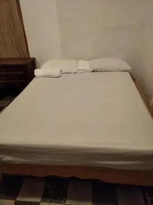 a bed with two white sheets on top of it at La casa de Jessica in Santo Domingo