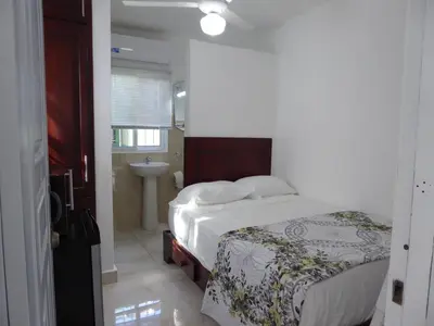 a bedroom with a bed and a bathroom with a sink at Cozy Studios-Private Entrance- HS Internet-AC-Hot Water-Backup Generator-near the Beach in San Felipe de Puerto Plata