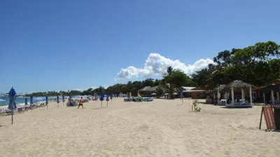 a sandy beach with chairs and umbrellas and the ocean at Cozy Studios-Private Entrance- HS Internet-AC-Hot Water-Backup Generator-near the Beach in San Felipe de Puerto Plata
