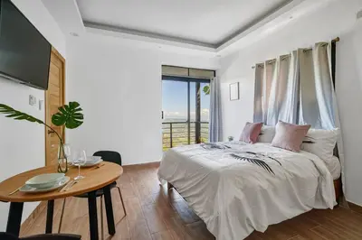 a bedroom with a bed and a table and a window at Villa Favella-Pop-Art-View-7BR-Jamaca De Dios-Balcony-Dream in Jarabacoa