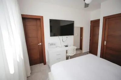 a bedroom with a bed and a flat screen tv at Soha suites I in Santiago de los Caballeros