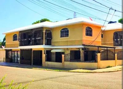 an orange and yellow building with a gate at Hospedaje de marant 1 in San Felipe de Puerto Plata
