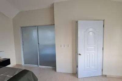 a bedroom with a white door and a glass closet at El más completo, a menos de 5 minutos de la playa, free wifi fuera del alojamiento in San Felipe de Puerto Plata